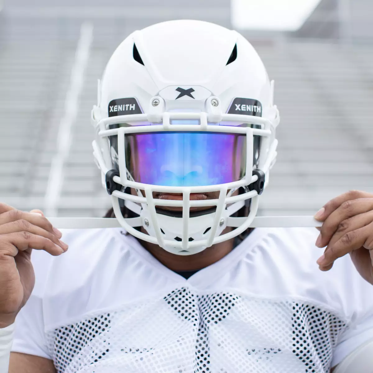 Close up of a player facing the camera, pulling the Adaptive Fit chin straps outward.